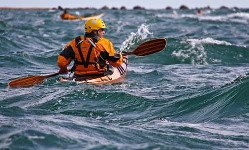 Kayaker in a yellow helmet paddling through choppy tidal water