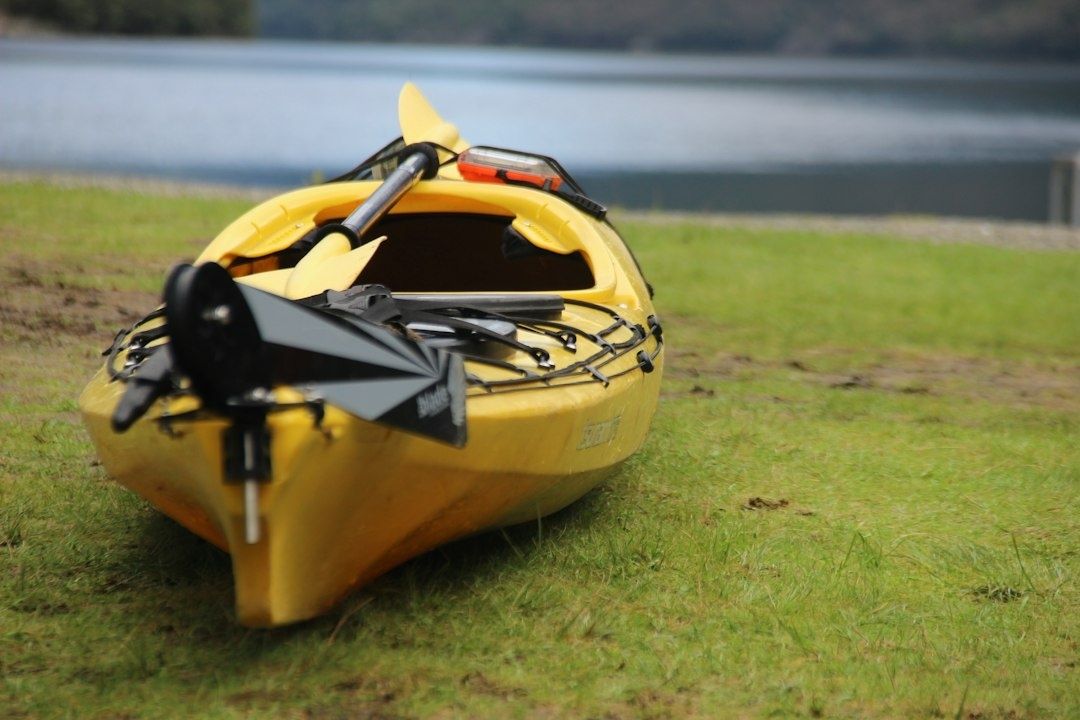 Yellow sea kayak with paddle and cockpit gear on grassy shore
